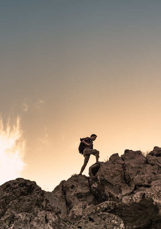 A man carries a rucksack and walks on rocks