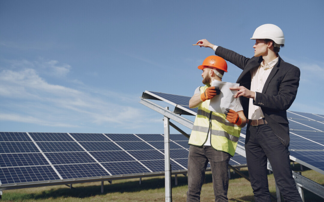 A site manager and a worker point at solar panels