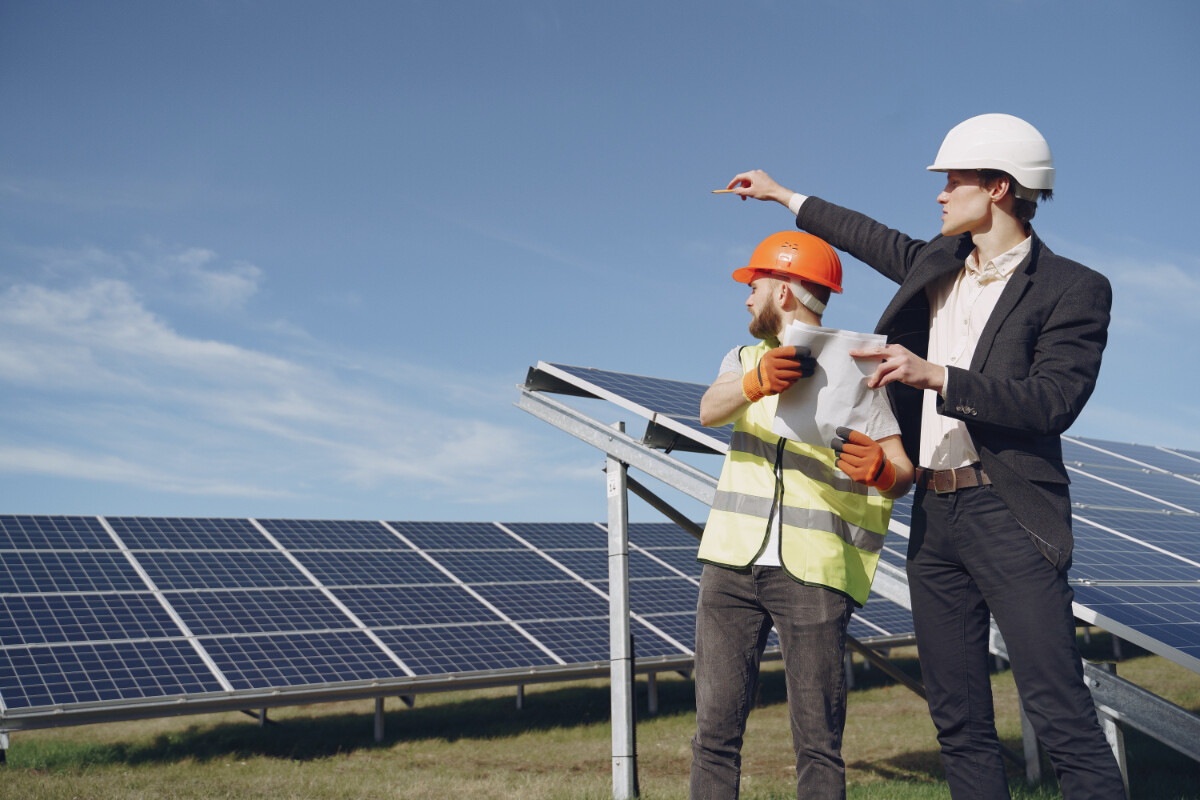 A site manager and a worker point at solar panels