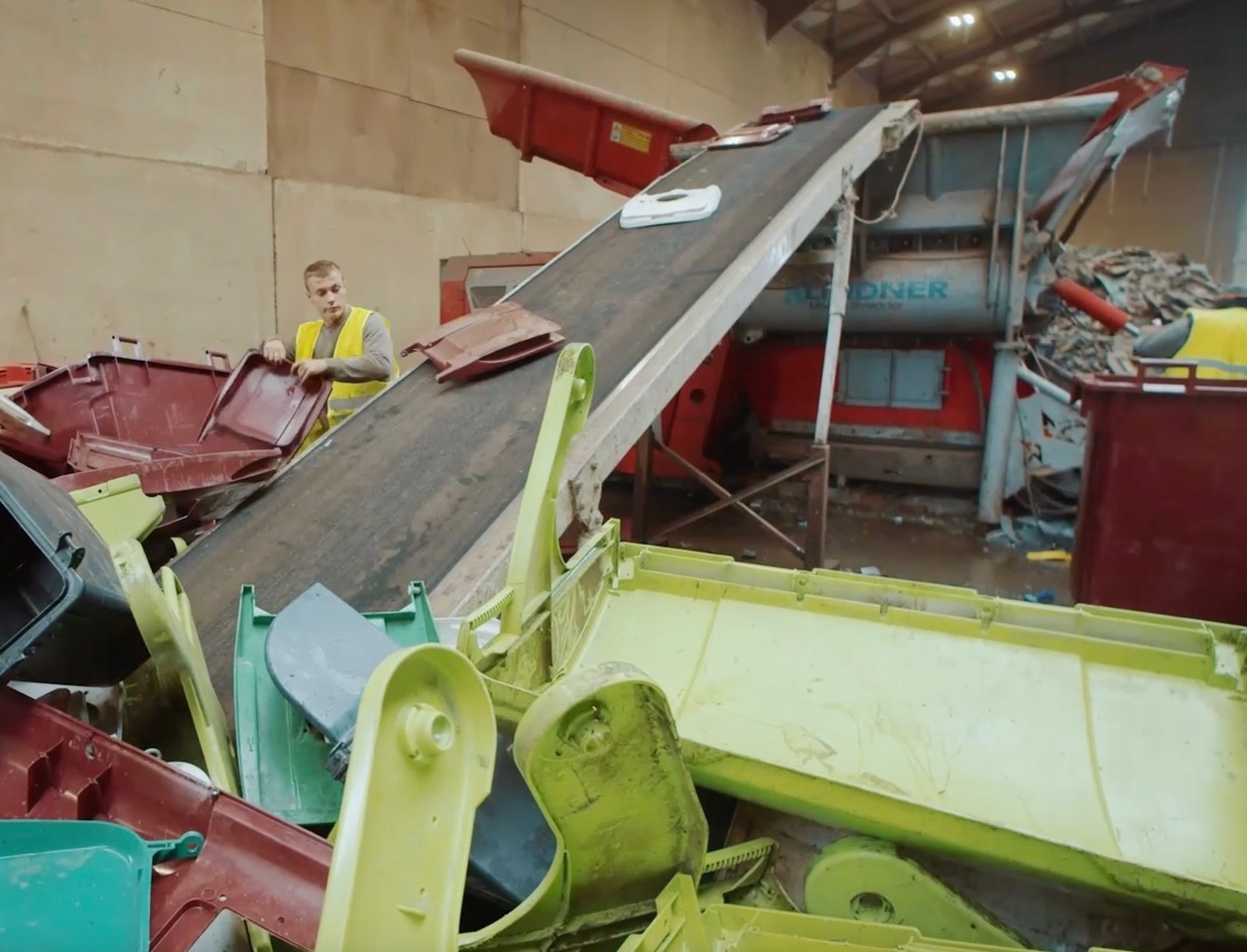 A worker at a waste treatment plant, the central device being a shredding machine marked ‘Herbold’